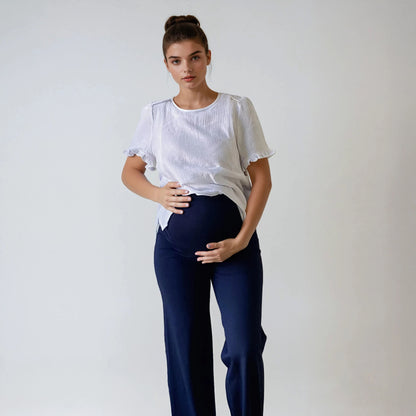 Femme enceinte portant le pantalon Cosy bleu marine, coupe droite, taille haute douce et extensible, sur fond studio blanc.