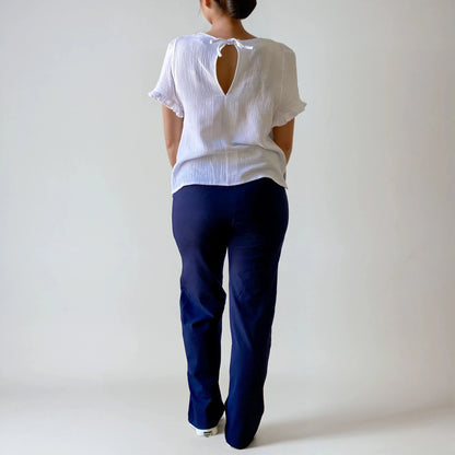 Femme enceinte de dos portant le pantalon Cosy bleu marine, coupe droite, taille haute douce et extensible, sur fond studio blanc.